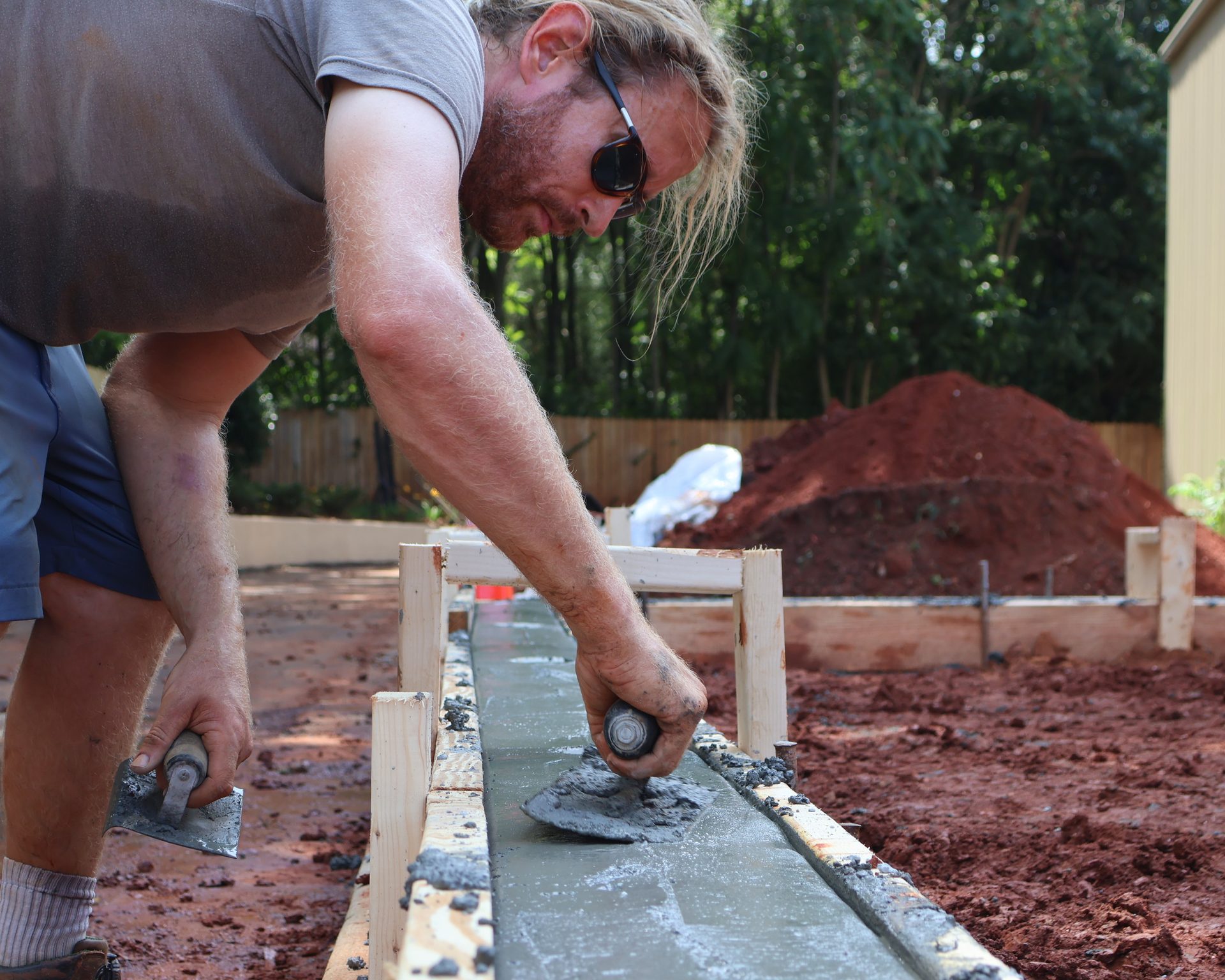 Pro Play crew member placing concrete around footings beside an installed slide