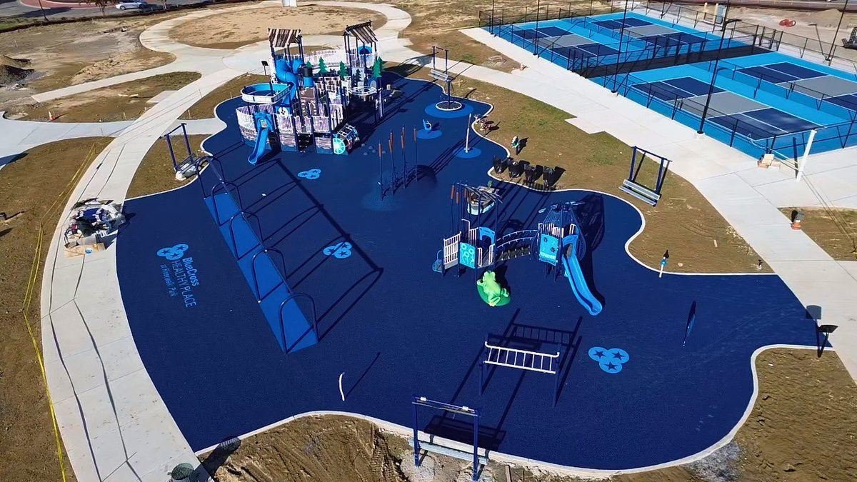 Aerial view of BCBS Healthy Place at Riverwalk Park, with fitness equipment and play structures on navy poured surfacing