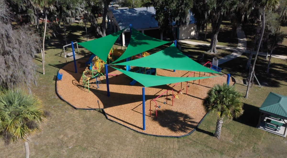 Aerial view of the Pettis Park playground, with green sail shades over a colorful play structure and wood-fiber surfacing
